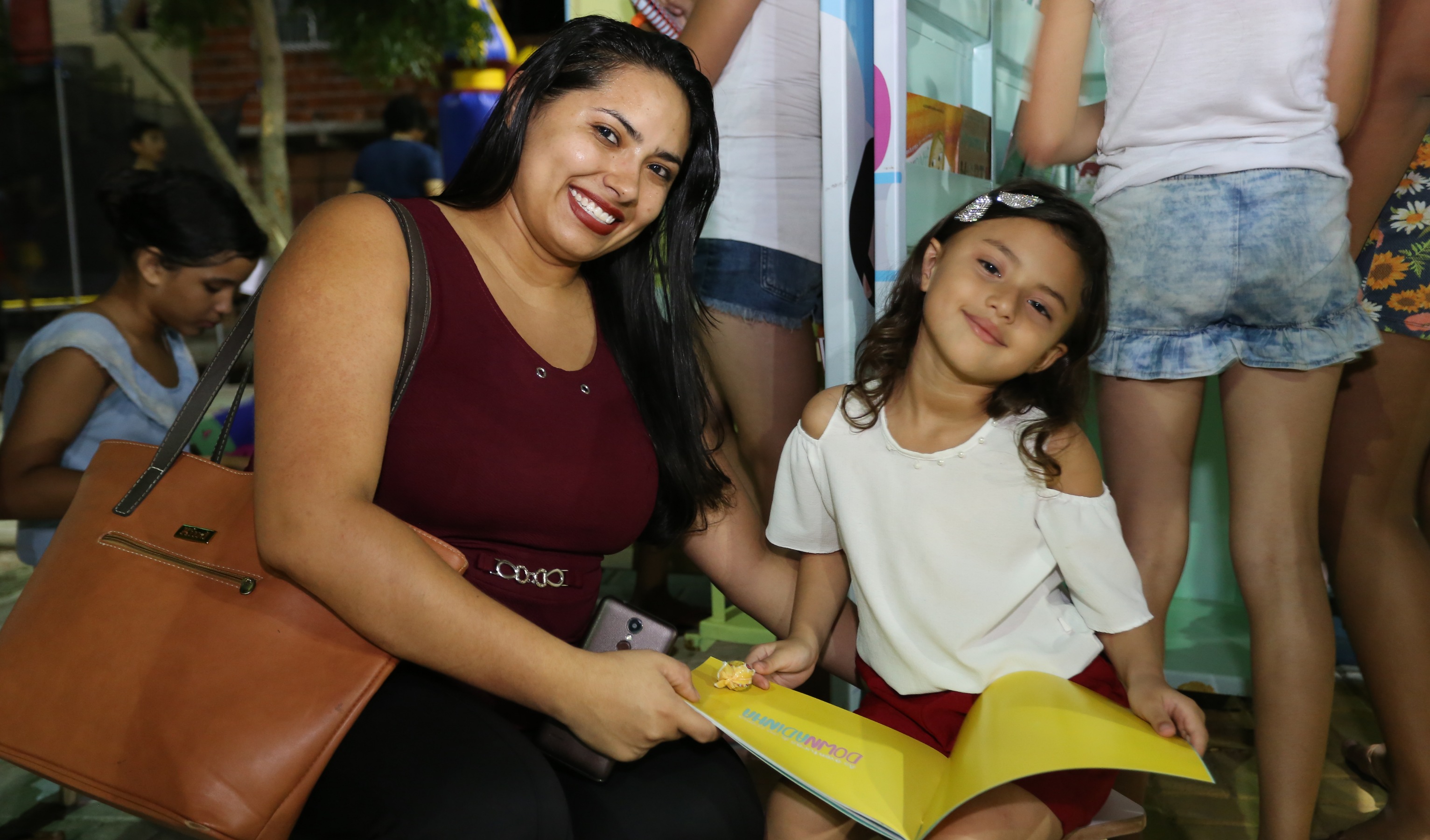 mulher e criança posam para a foto segurando um livro